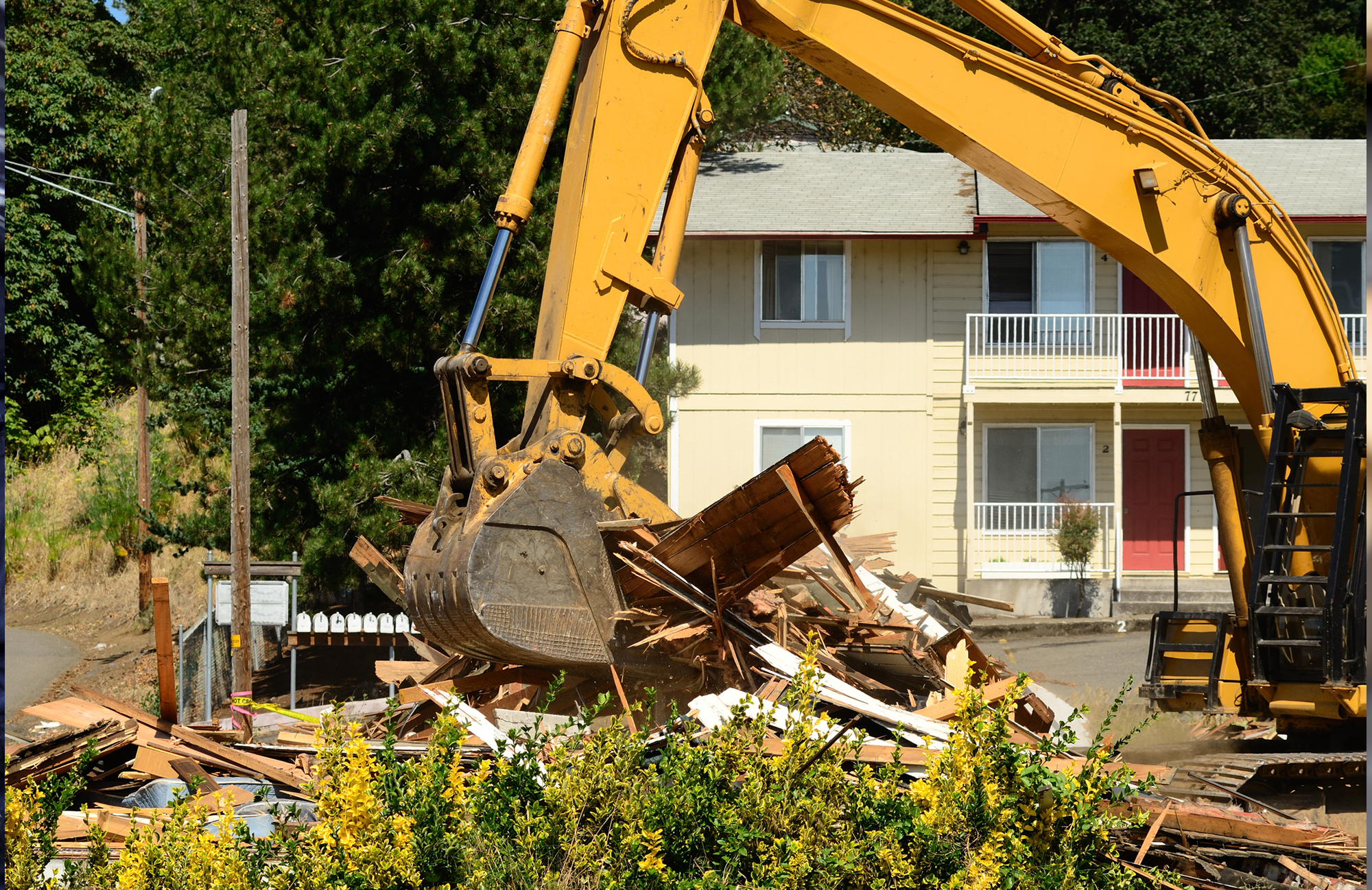 A Large Track Hoe Excavator Tearing Down House Damages